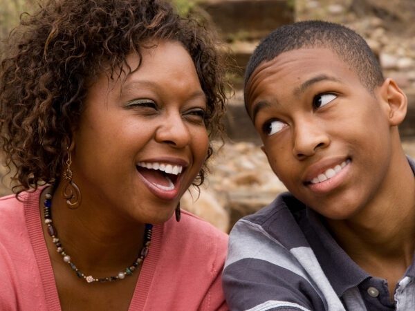 Black mom laughing with her teenage son with the title