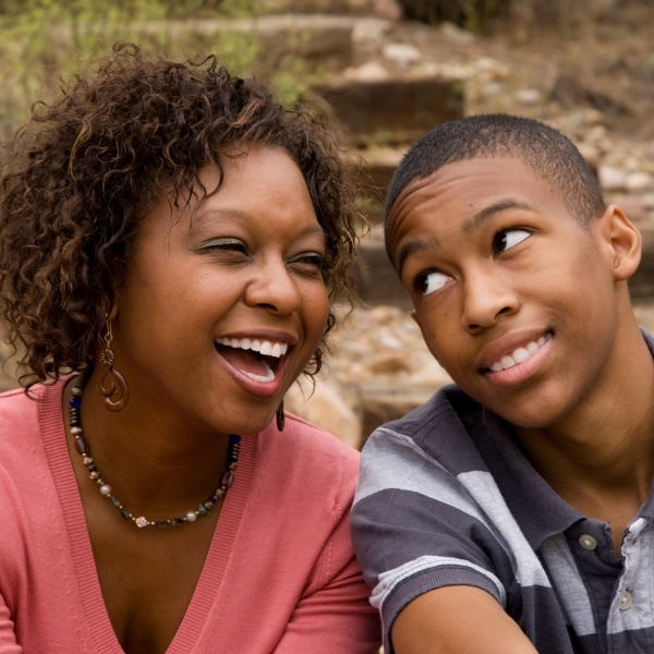Black mom laughing with her teenage son with the title