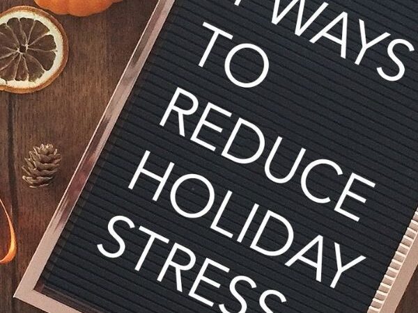 Felt letter board titled "4 Ways to Reduce Holiday Stress" next to dried orange slices, a pumpkin, and pinecones