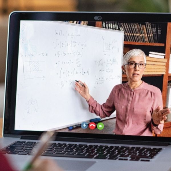 closeup of a laptop, teacher on the screen in front of a white board with math on the board