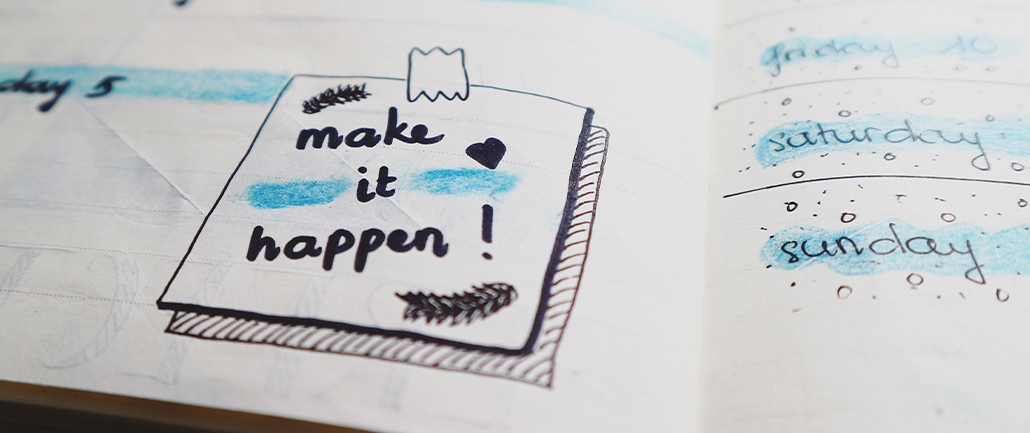 planner open to a doddle of drawing that says "Make it Happen!" with blue highlights