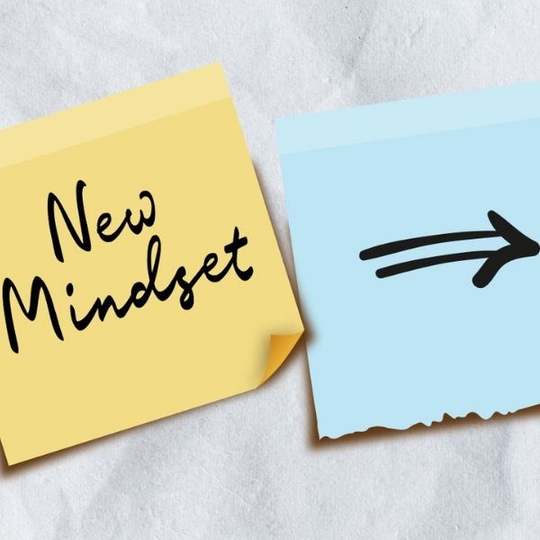 two post-it notes, the one on the left says "New Mindset", the one on the left has an arrow that points to the right