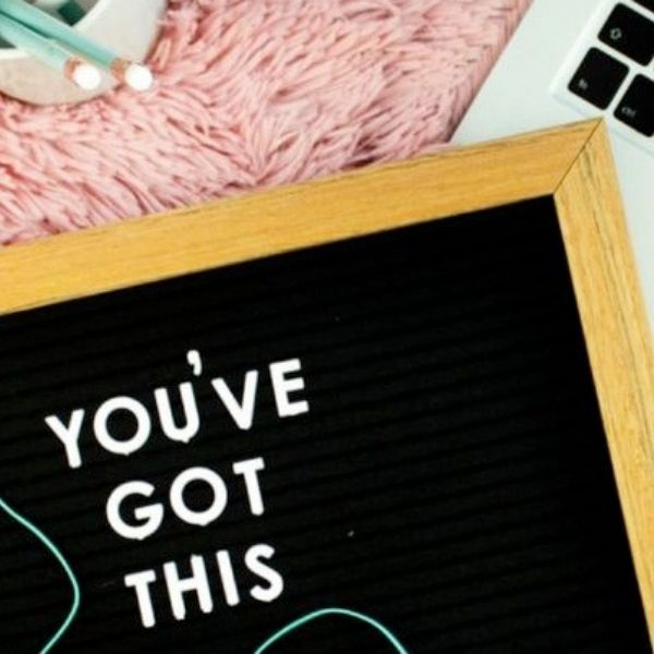close up of a felt board sign that reads "You've Got This" on top of a laptop and pink rug