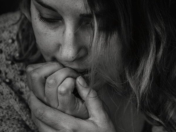 a close up of a black and white image of a pensive young woman with her hands to her face