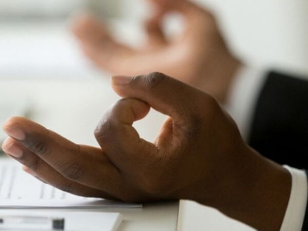 closeup of a black person wearing a formal work suit, meditating at their work desk