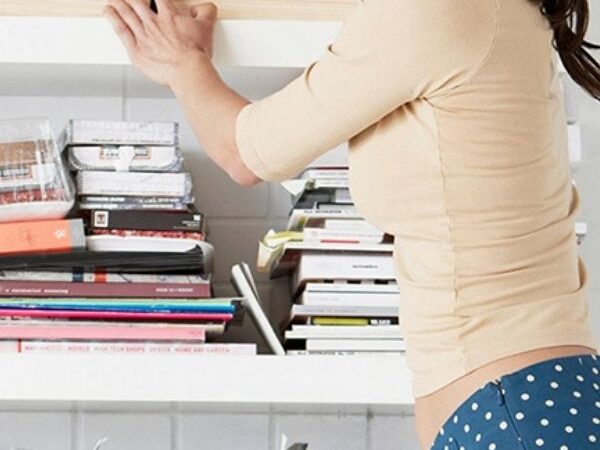 female looking through multiple shelves filled with magazines and books